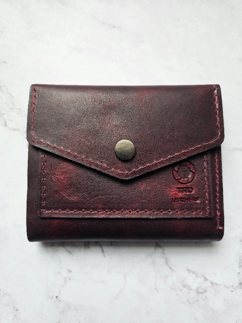 A red leather snap wallet closed with a snap button.