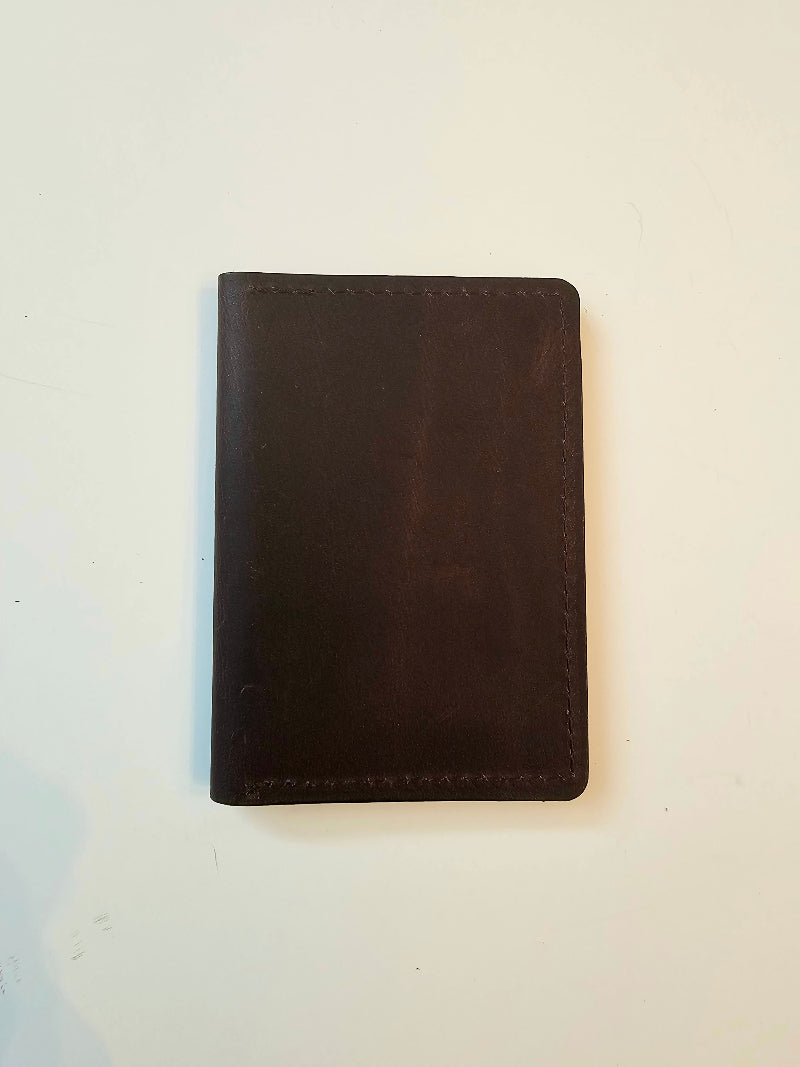 Dark brown leather wallet on a light beige background