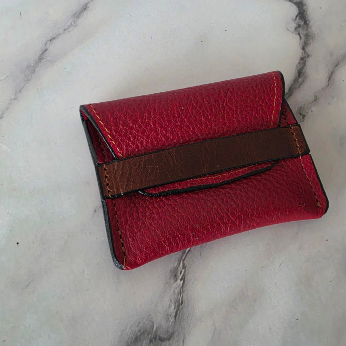 Crimson pebbled leather pouch with brown keeper band, side angle