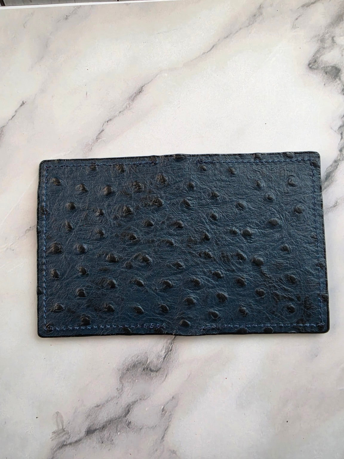 Midnight blue textured leather ID wallet — exterior view on marble