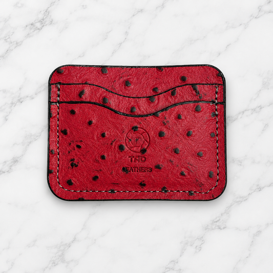 Ruby red textured leather cardholder front with Tad Leathers stamp on marble