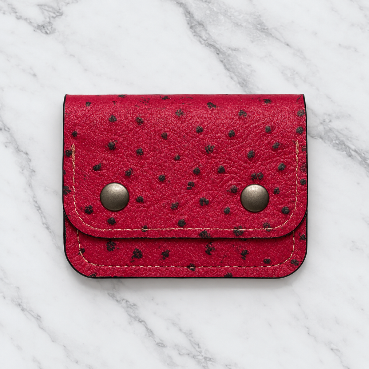 Ruby red textured snap wallet upright on marble