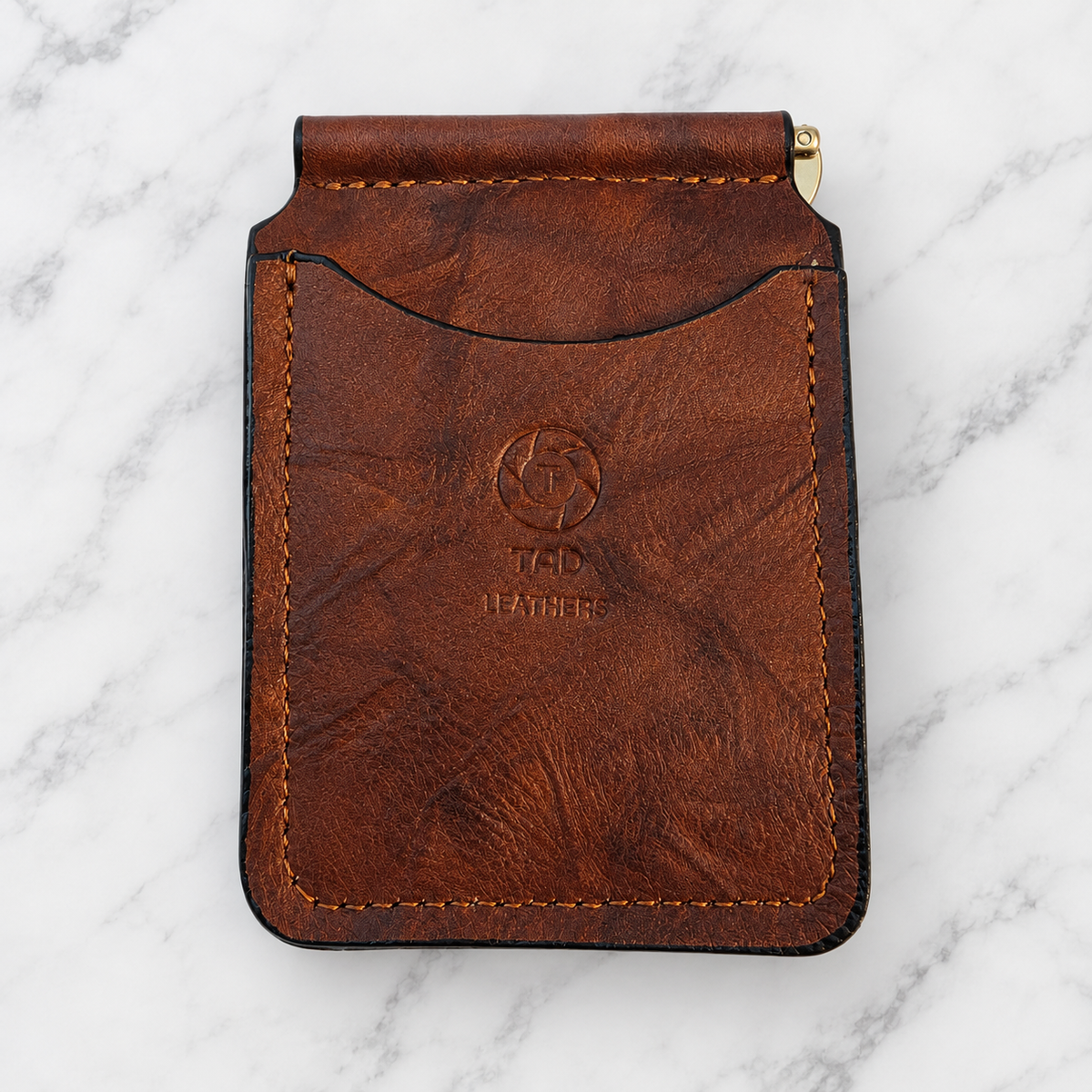 Rustic brown leather money clip wallet, front view on marble