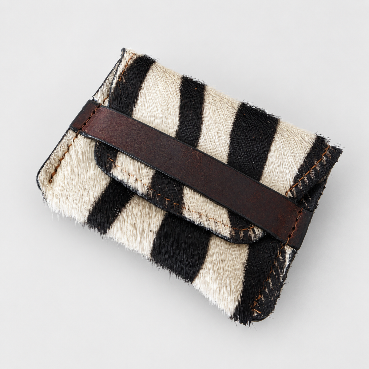 Zebra-pattern hair-on-hide leather pouch with brown leather band, angled view