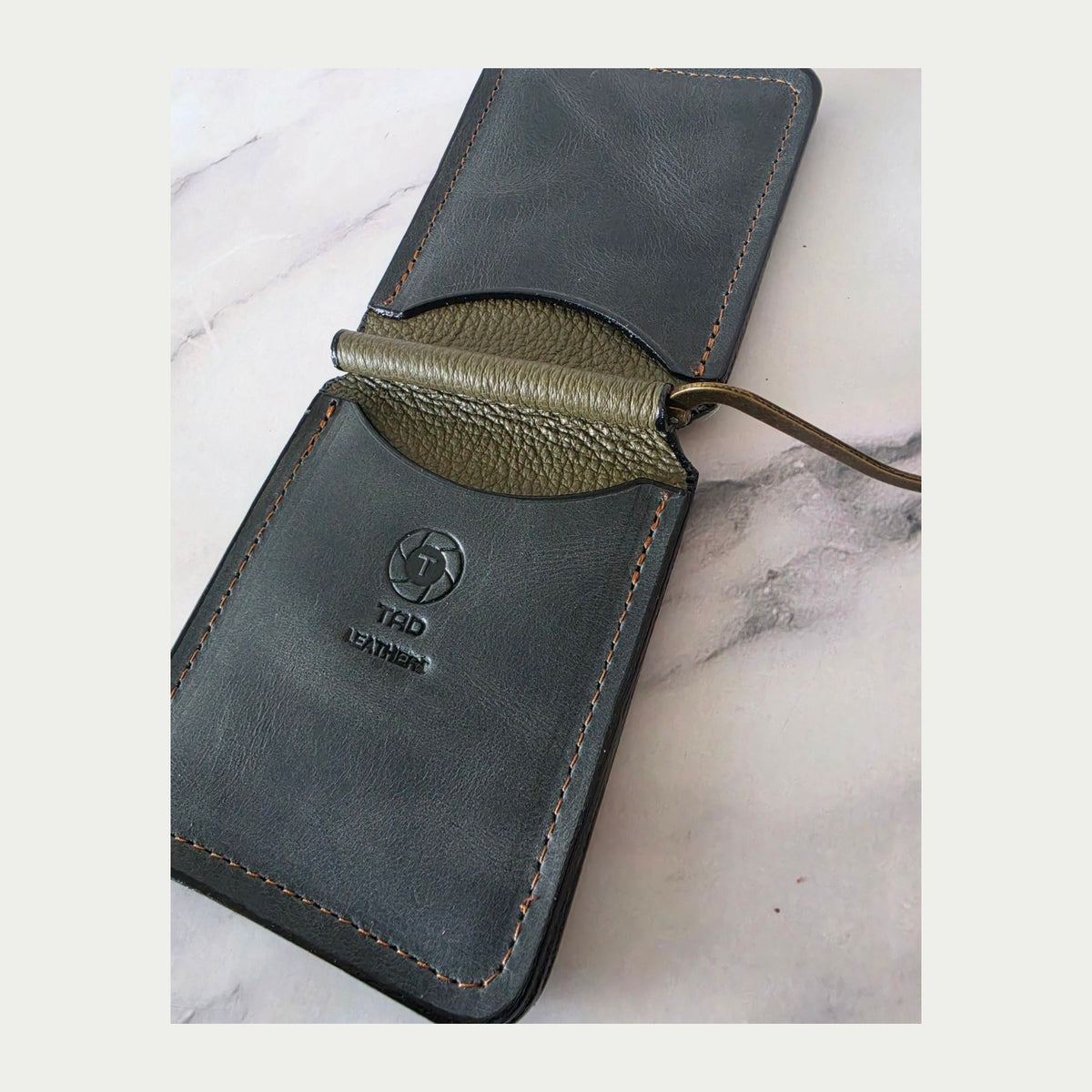 Close view of charcoal leather card pockets and olive spring-bar center