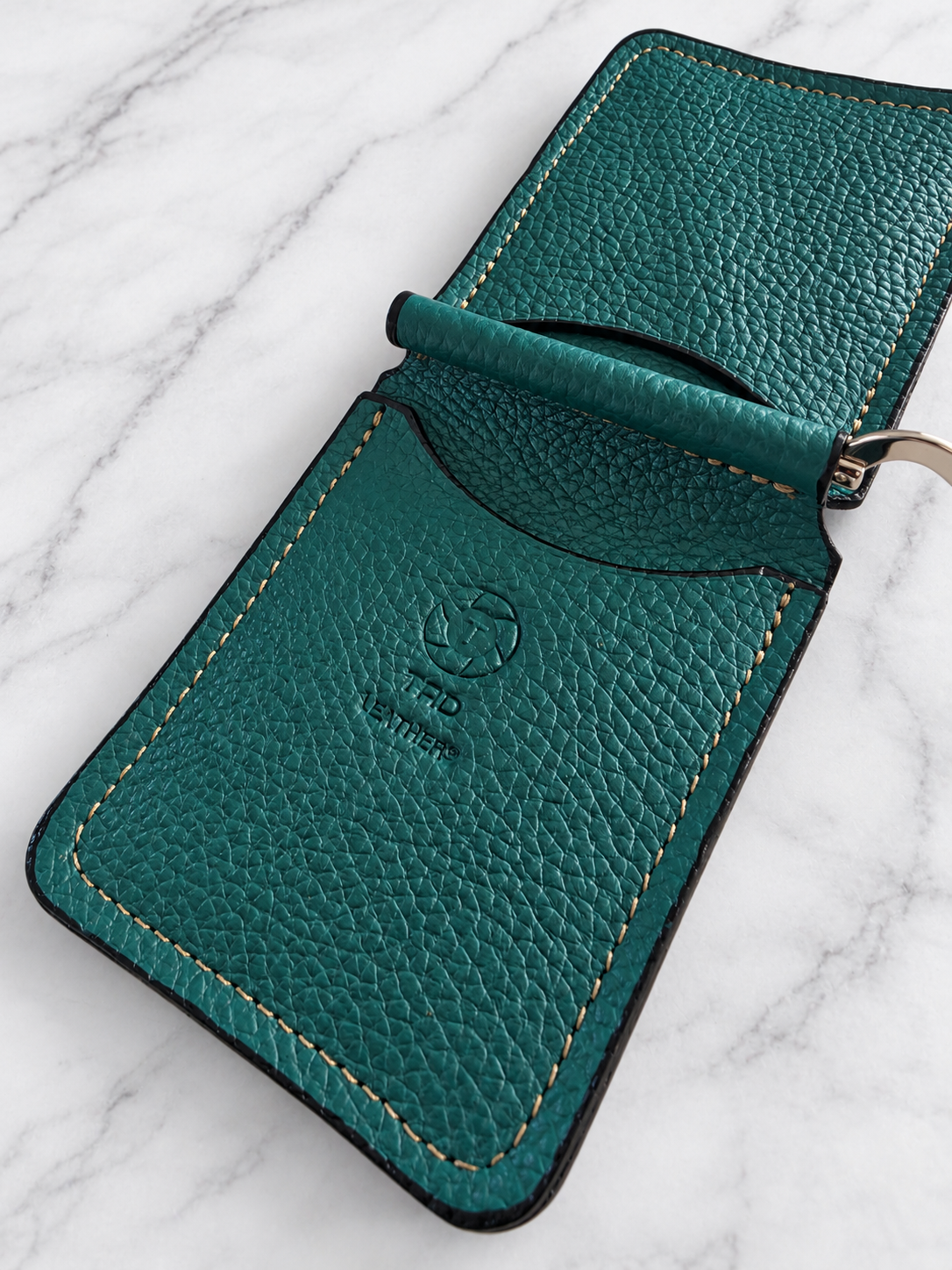 Close-up of teal pebbled leather, tan stitching and Tad Leathers stamp