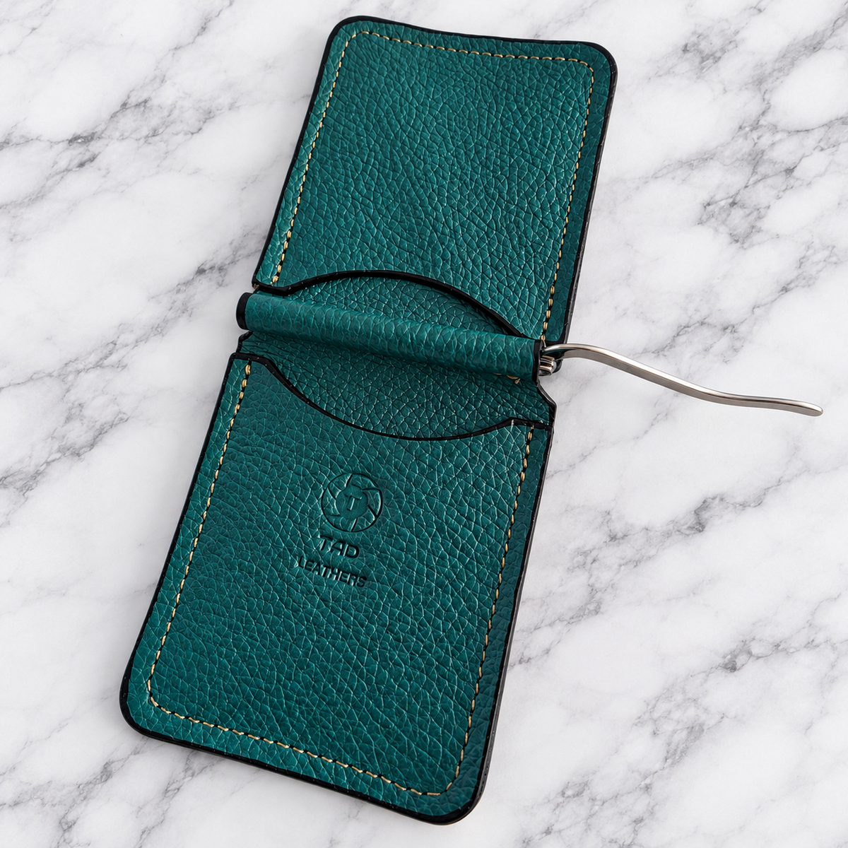 Open teal leather wallet showing card pockets and silver spring money clip